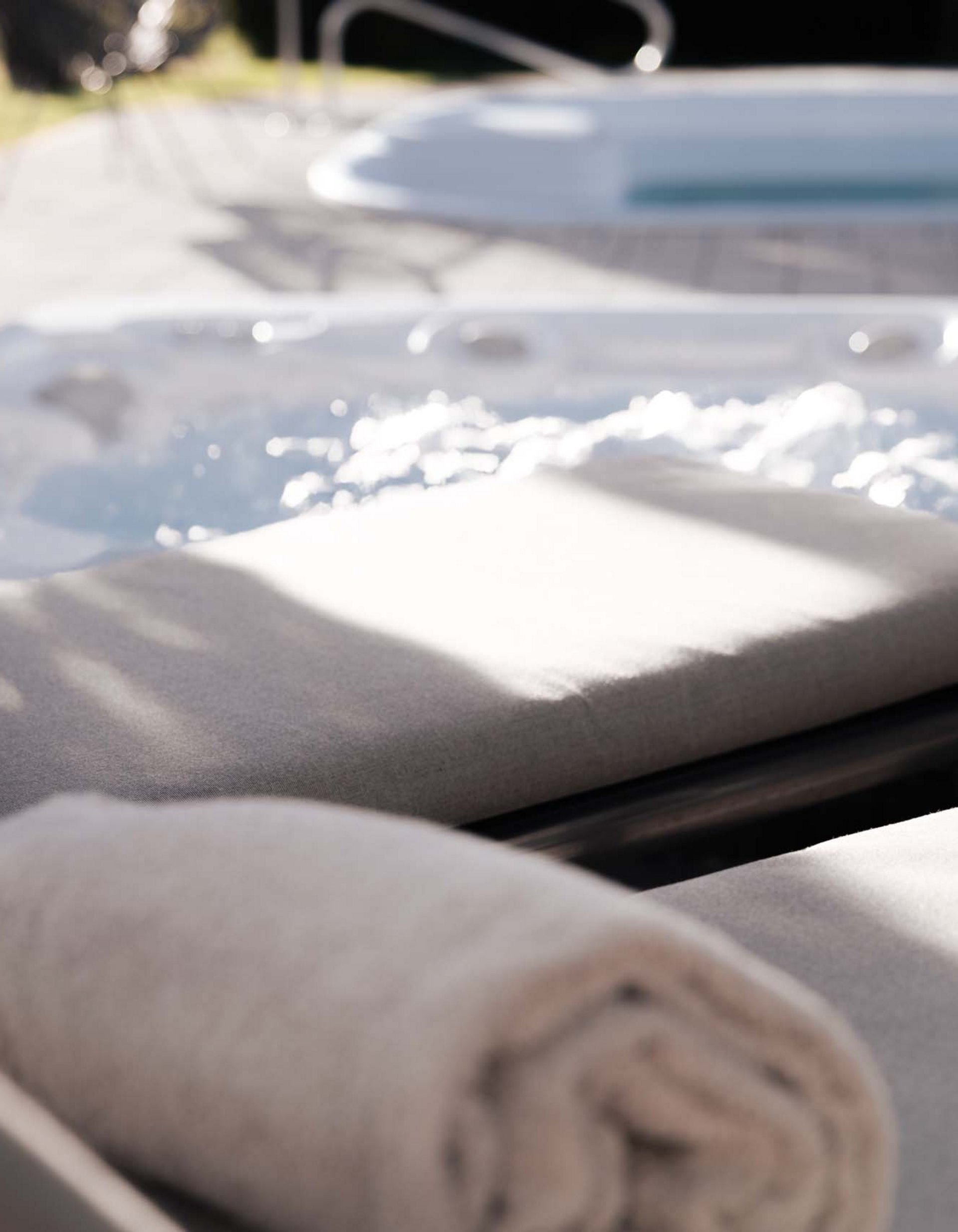 Due asciugamani su lettini accanto a una vasca idromassaggio all'aperto