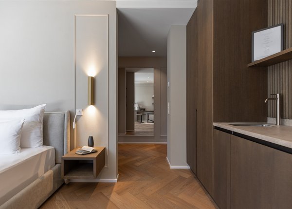 Lingers Junior Suites Moderner Schlafzimmerbereich mit Bett, Nachttisch und Küchenschrank