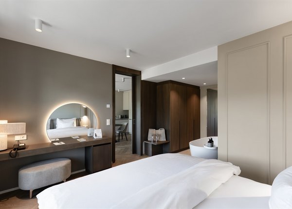 Luxus Apartment II Modernes Schlafzimmer mit weißem Bett und beleuchtetem Rundspiegel