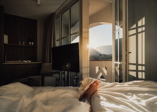 Lingers Junior Suites Blick vom Bett in einem Hotelzimmer mit offenem Balkon und Sonnenaufgang