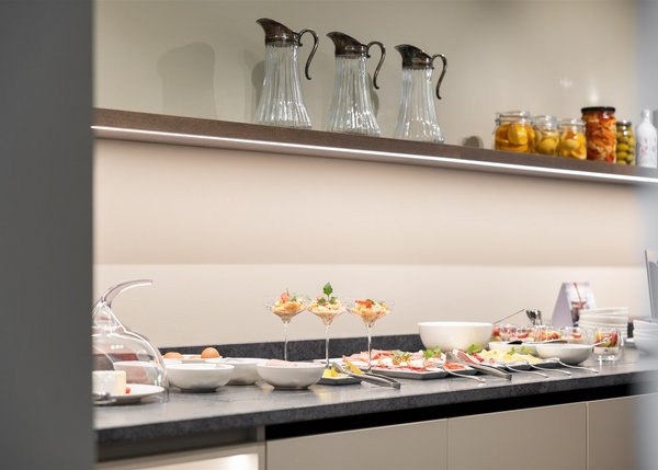 Buffet mit Gläsern, Servierplatten, Schüsseln und eingemachten Früchten auf einem Tisch