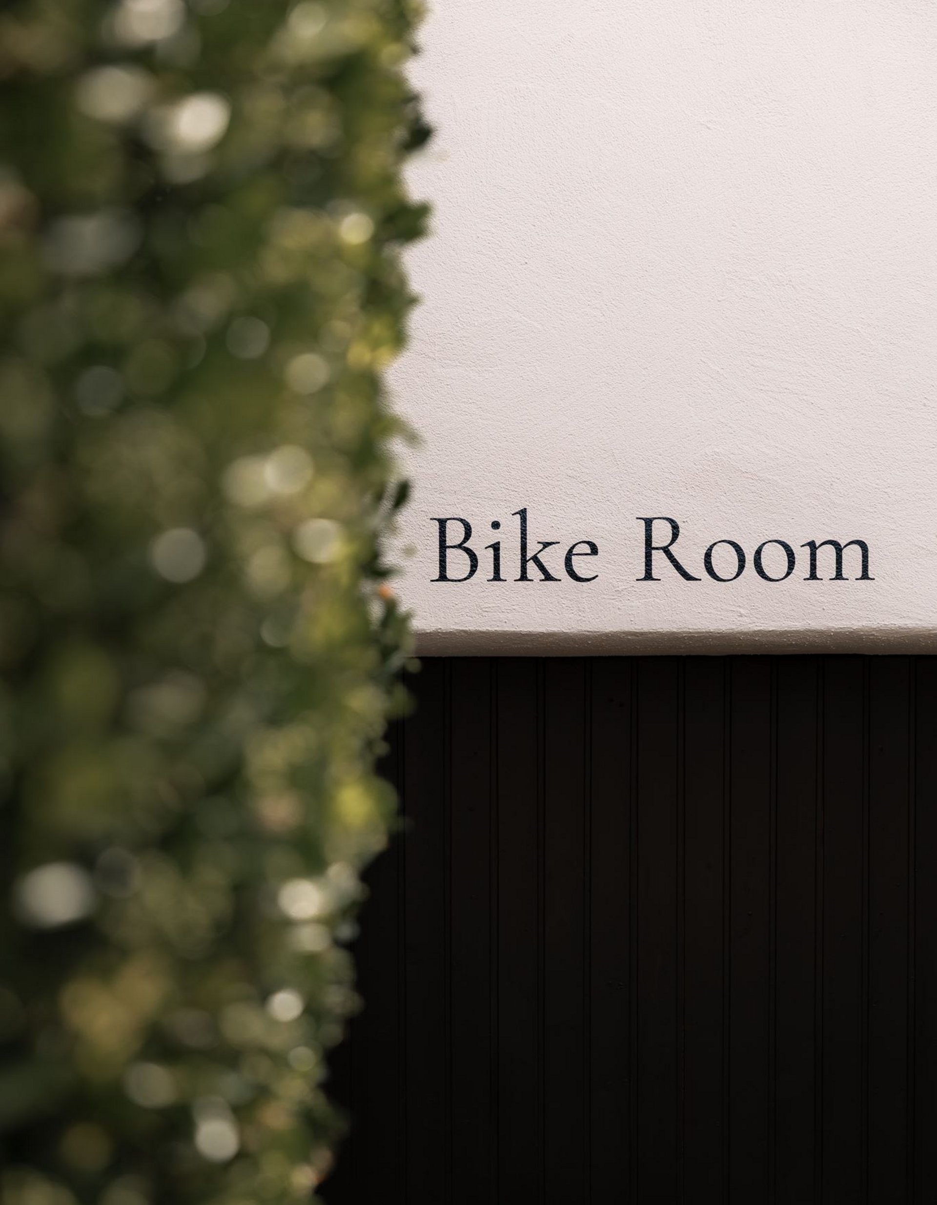Gli scatti più belli del Lingers Cartello con scritto Bike Room su muro bianco accanto a piante verdi