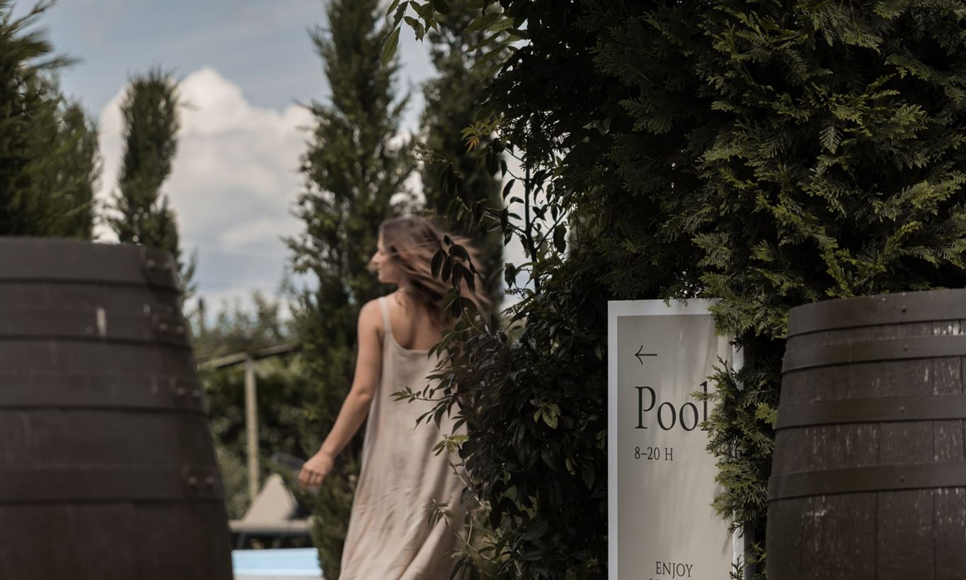 Gli scatti più belli del Lingers Donna con vestito chiaro cammina nel giardino verso la piscina