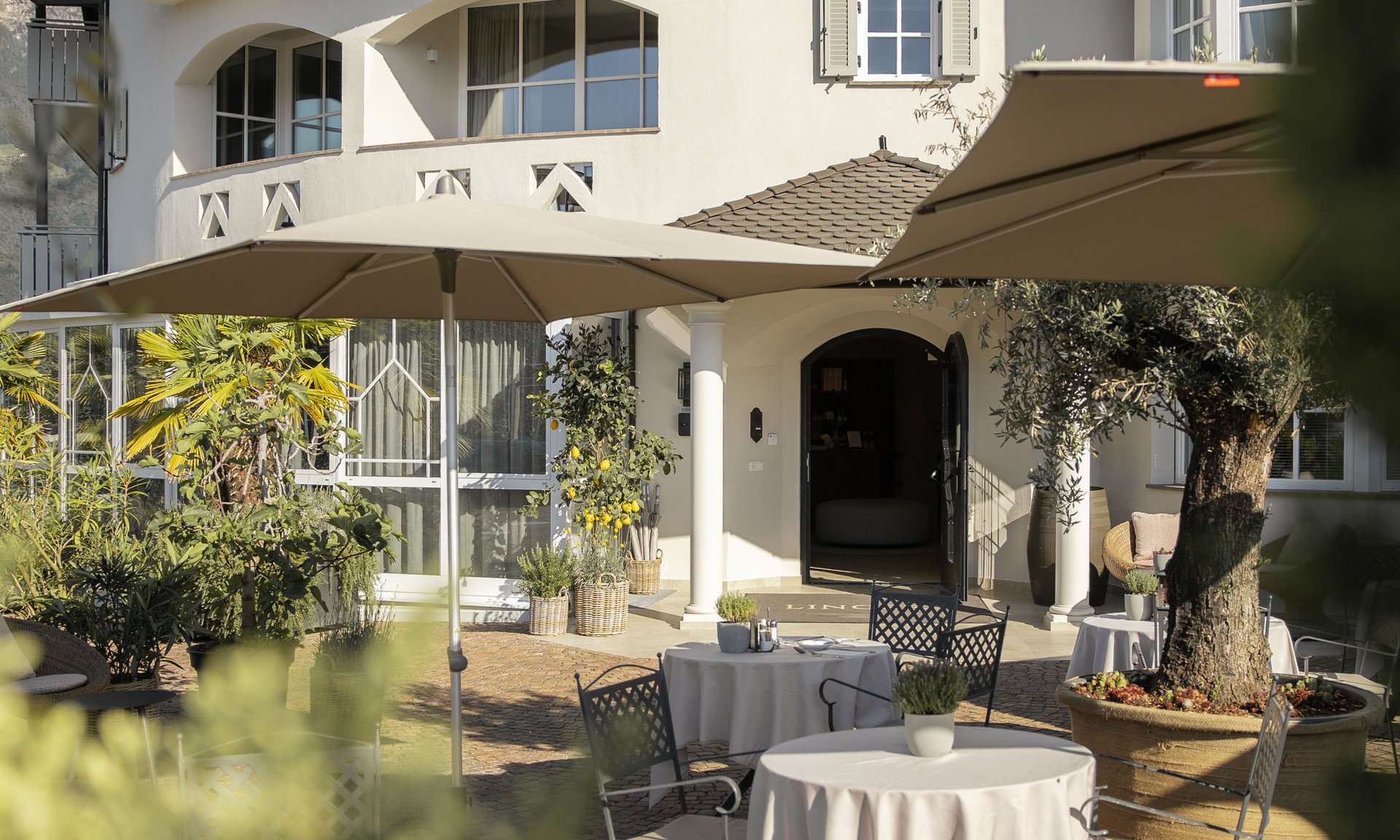 Außenbereich der Lingers Suites & Residence mit Tischen, Stühlen und Sonnenschirmen