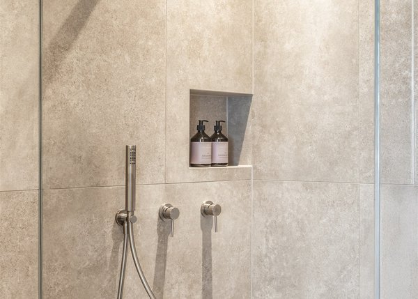 Apartment I Moderne Dusche mit Regenduschkopf und Shampoo-Flaschen in der Nische
