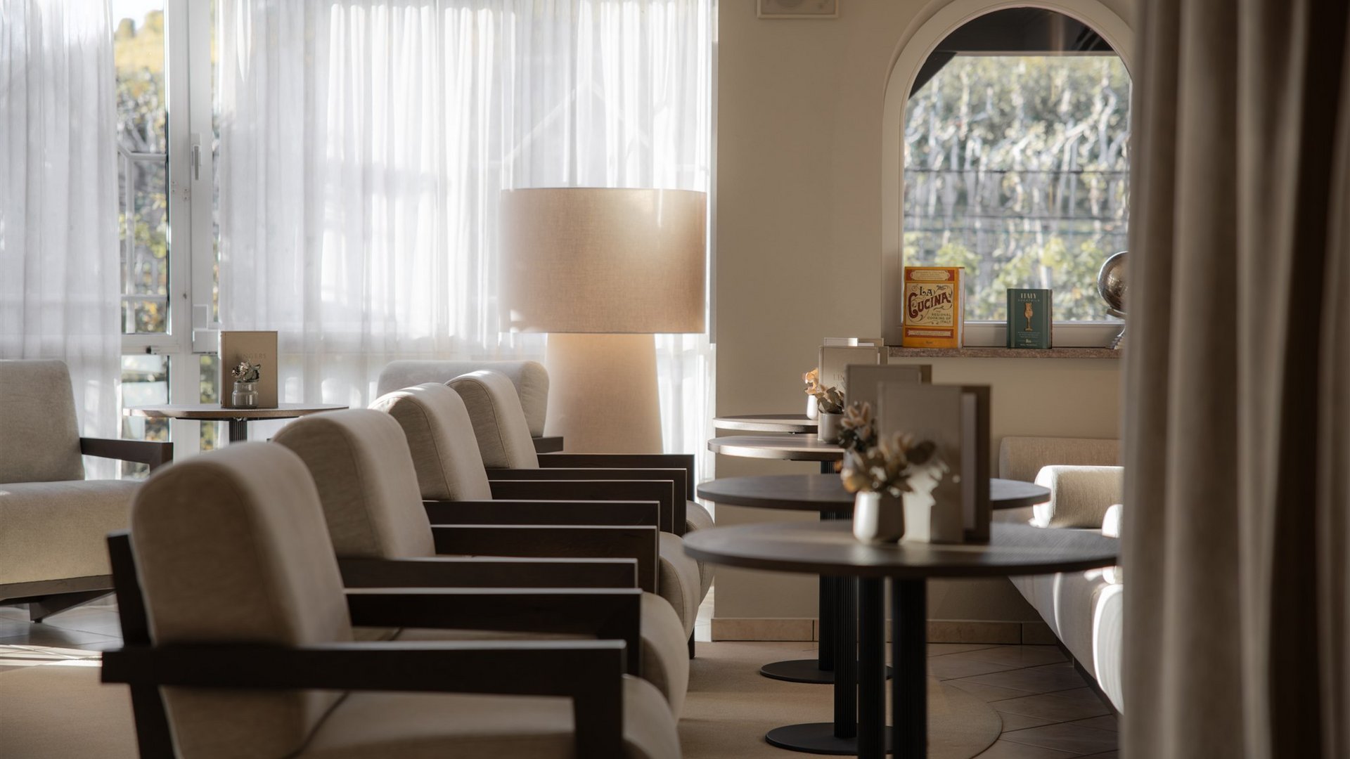 Area d'attesa illuminata con poltrone, tavoli e una lampada da terra