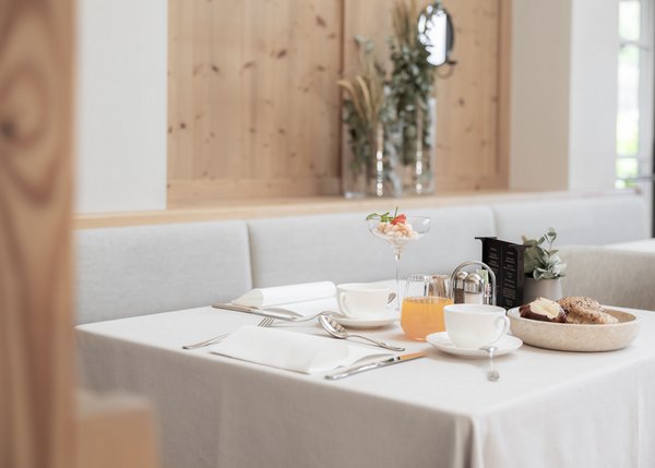 Tisch mit Besteck, Tassen, Orangensaft und Backwaren in modern eingerichteter Gastronomie