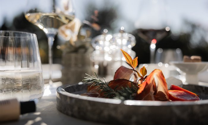 Antipasti-Platte mit Schinken, Tomaten und Kräutern bei Sonnenlicht