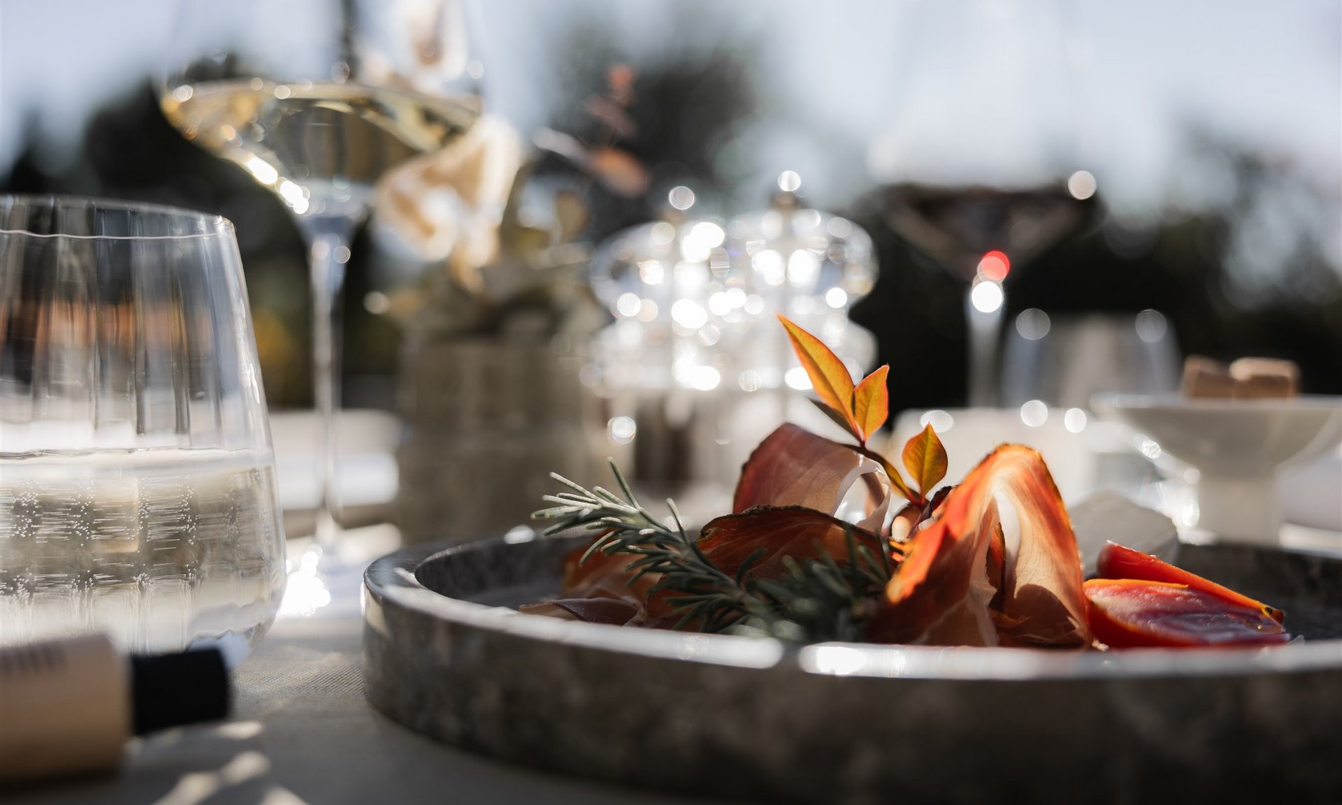 Piatto di antipasti con prosciutto, pomodori e erbe alla luce del sole