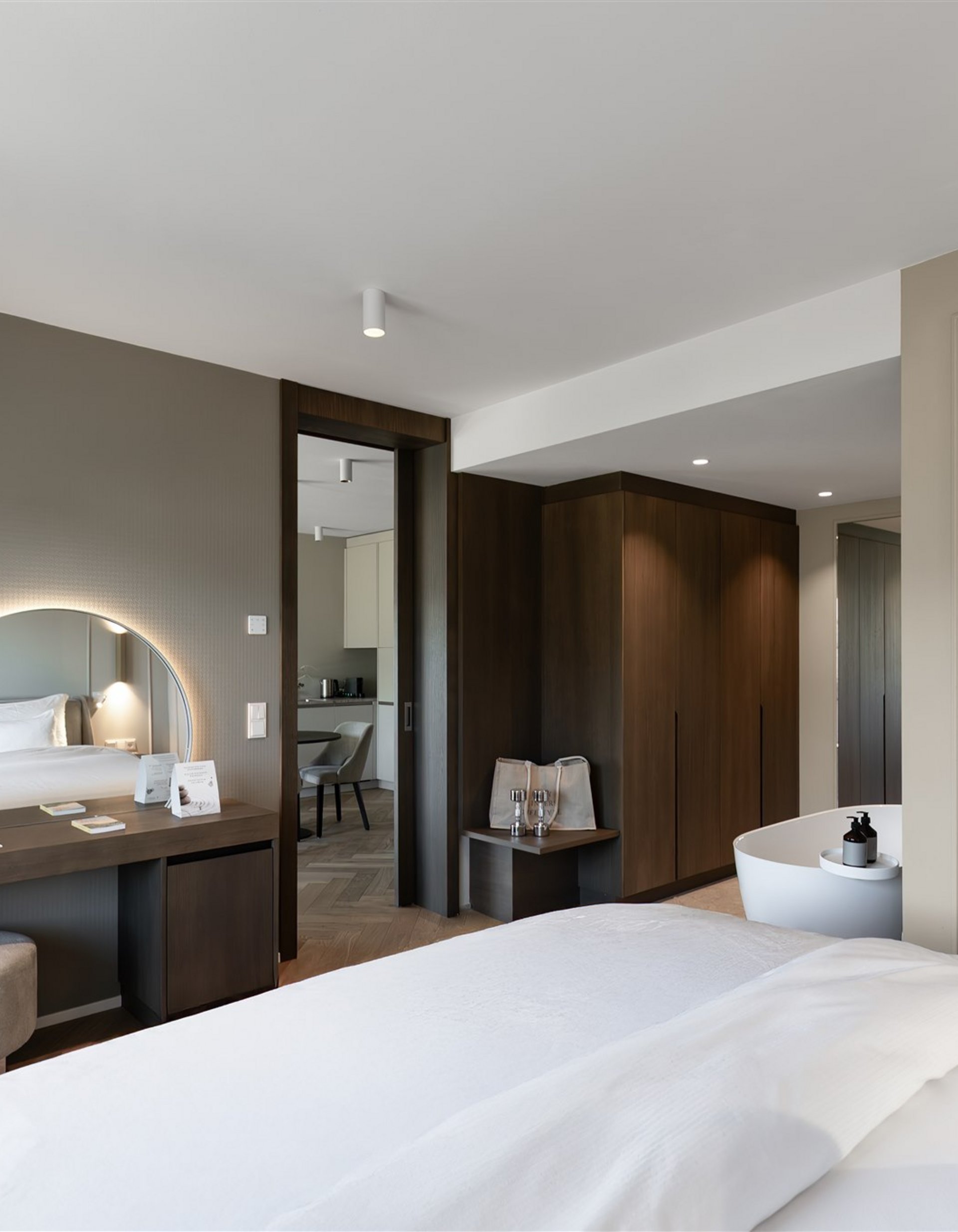 Camera d'albergo moderna con letto, specchio illuminato e vasca da bagno