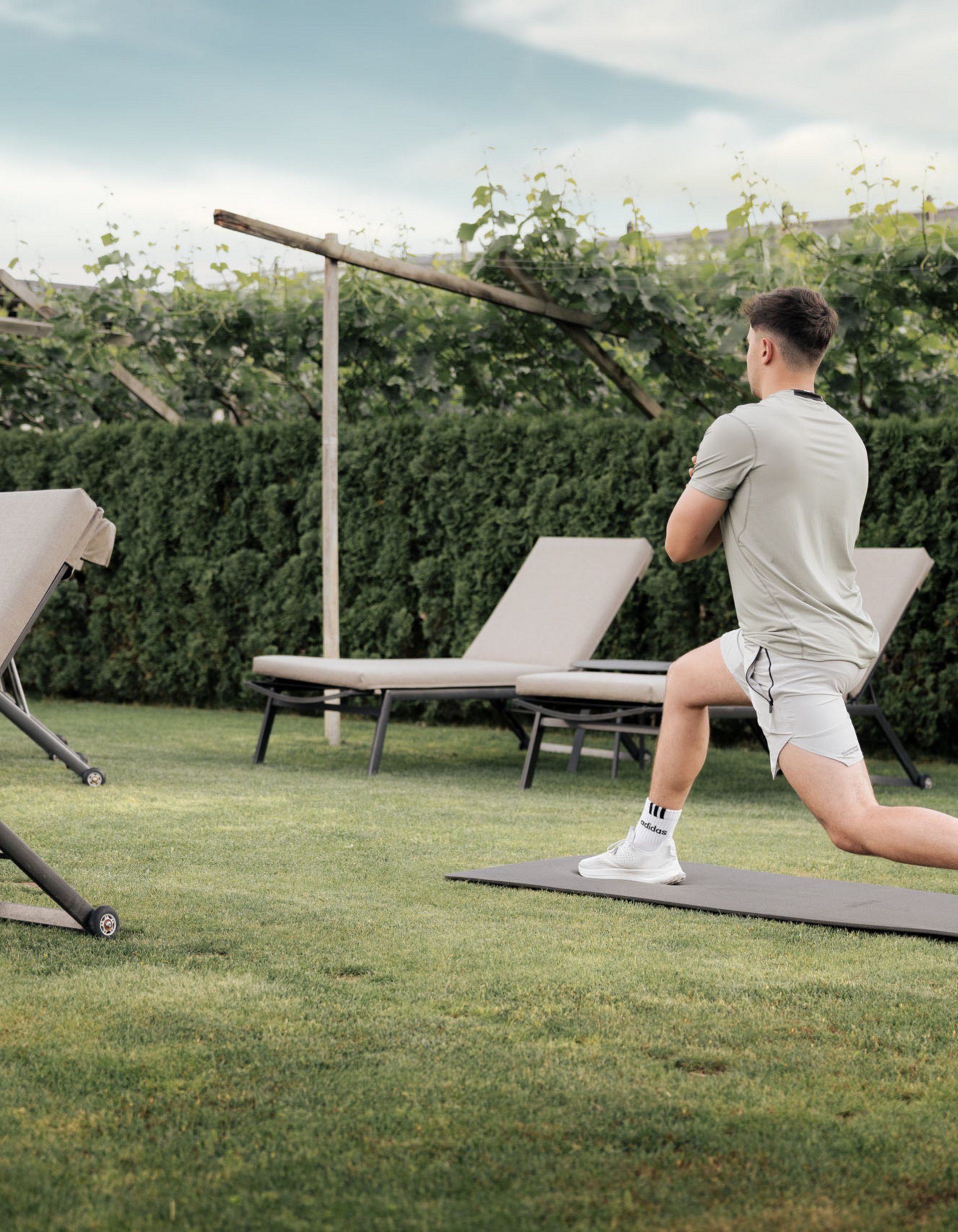 Uomo che fa stretching su tappetino in giardino vicino a lettini