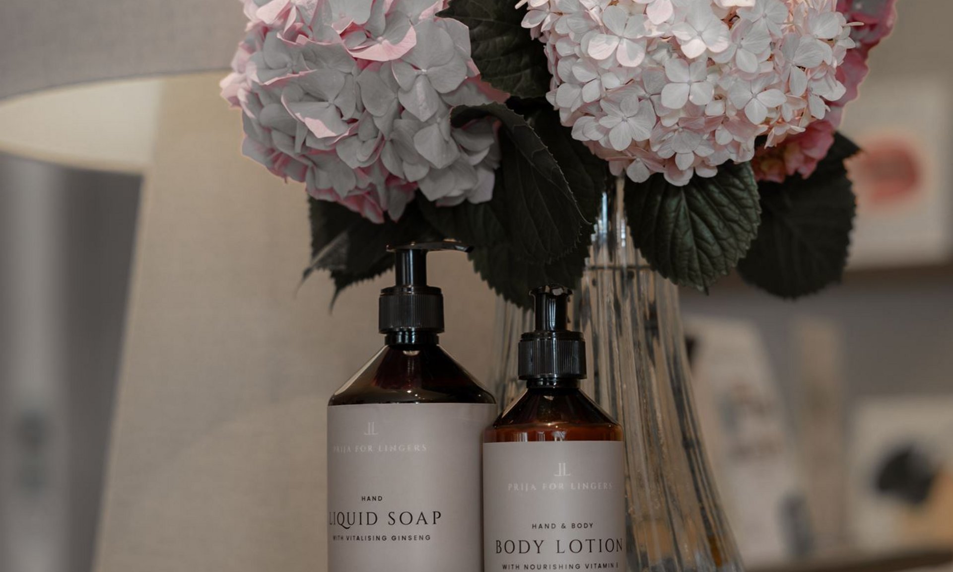 Gli scatti più belli del Lingers Bottiglie di sapone liquido e lozione corpo accanto a vaso con ortensie rosa