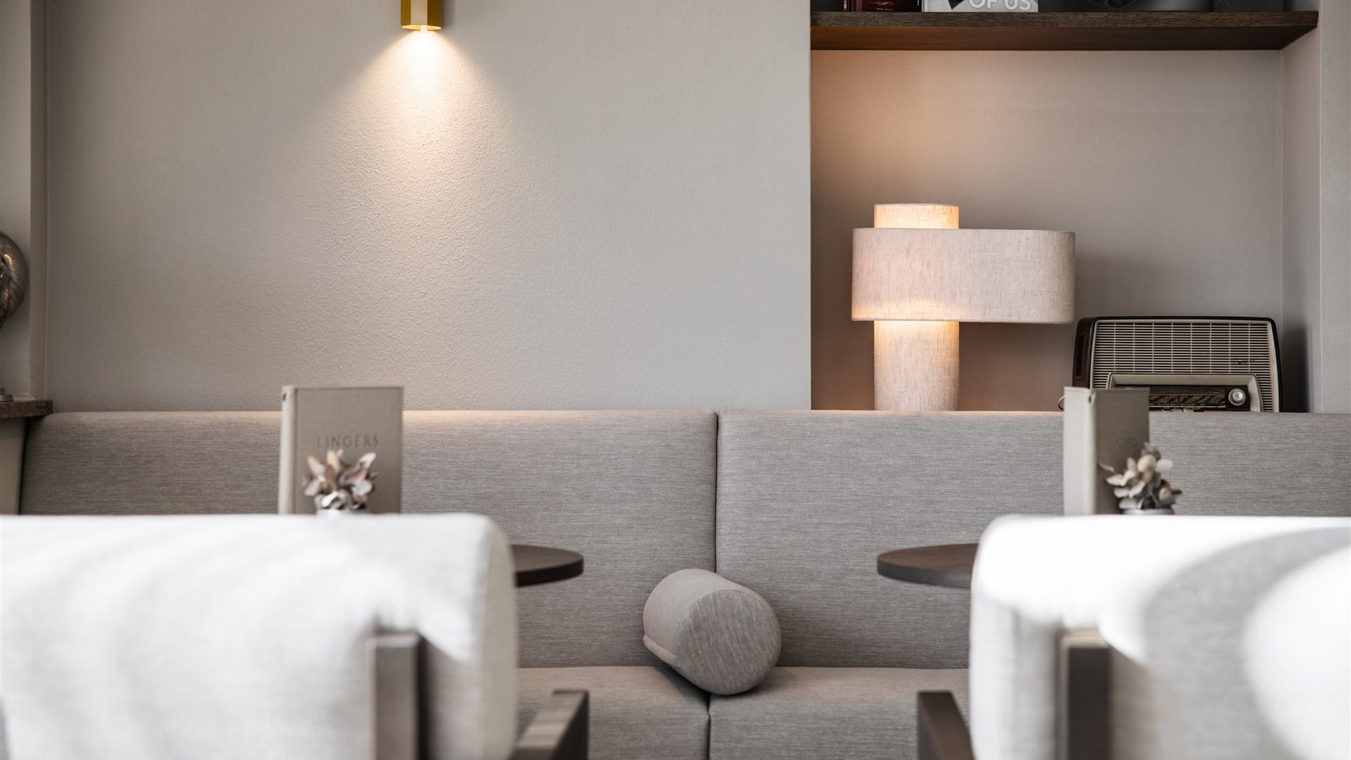 Moderner Sitzbereich mit grauem Sofa, zwei Tischen und sanfter Beleuchtung