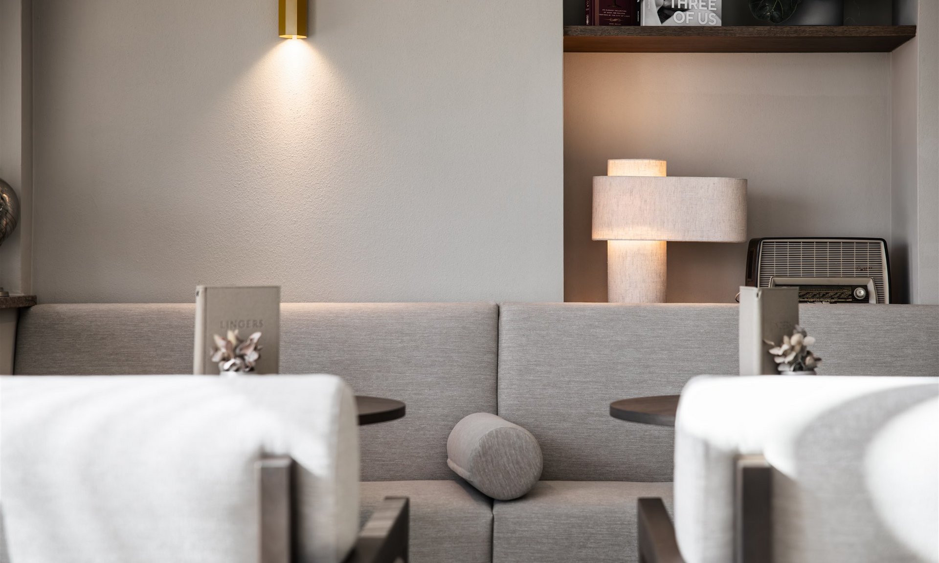 Area salotto moderna con divano grigio, due tavoli e illuminazione soffusa